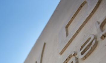 Betonwand mit Buchstaben vor blauem Himmel
