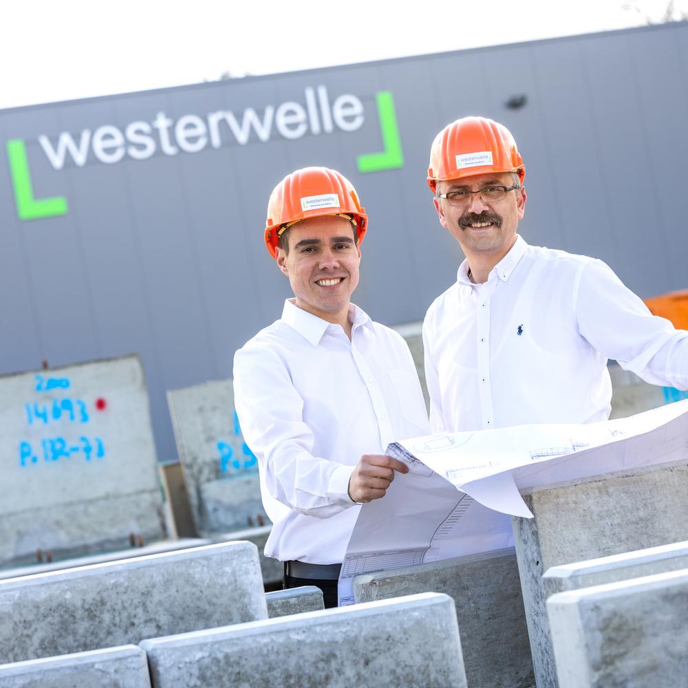 Zwei Mitarbeiter mit Helmen und Plan vor Westerwelle-Gebäude